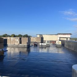 Rooftop view of an industrial building with HVAC units and a clear blue sky in the background.